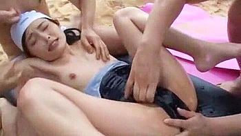 Two men finger her, give her a blowjob, and cum on her face.